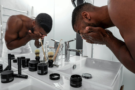 Black man washing face in the sink in the bathroom